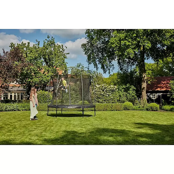 Salta Trampolin Comfort Edition - Durchmesser: 213 cm, Schwarz - Schwarzes Trampolin mit Sicherheitsnetz im Garten, ein Junge springt darauf, ein Mädchen schaut zu.