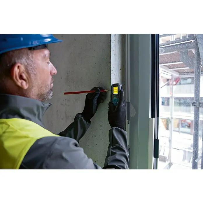 Bosch Professional Laserentfernungsmesser GLM 50-25 G - Messbereich: 0,05 - 50 m - Ein Bauarbeiter misst mit dem Bosch-Laser-Entfernungsmesser an einer Betonwand und markiert mit einem Bleistift die Messstelle.