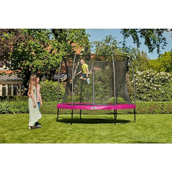 Salta Trampolin Comfort EditionDurchmesser: 213 cm, Pink - Ein Salta Trampolin im Garten, auf dem ein Kind springt, während zwei Personen zusehen. Das Trampolin hat einen pinkfarbenen Rahmen und ein Sicherheitsnetz.