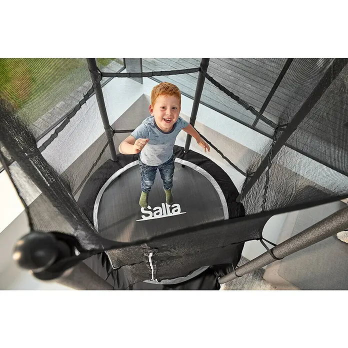 Salta Trampolin Junior - Durchmesser: 140 cm, Pink - Fröhlicher Junge auf einem Salta Trampolin mit Sicherheitsnetz. Ideal für sicheren Springspaß im Garten.