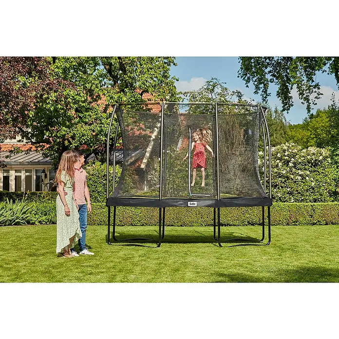 Salta Trampolin Comfort Edition - Schwarz, L x B: 244 x 366 cm - Eine Familie genießt einen sonnigen Tag im Garten mit einem rechteckigen Salta-Trampolin mit Sicherheitsnetz, während ein Mädchen springt.