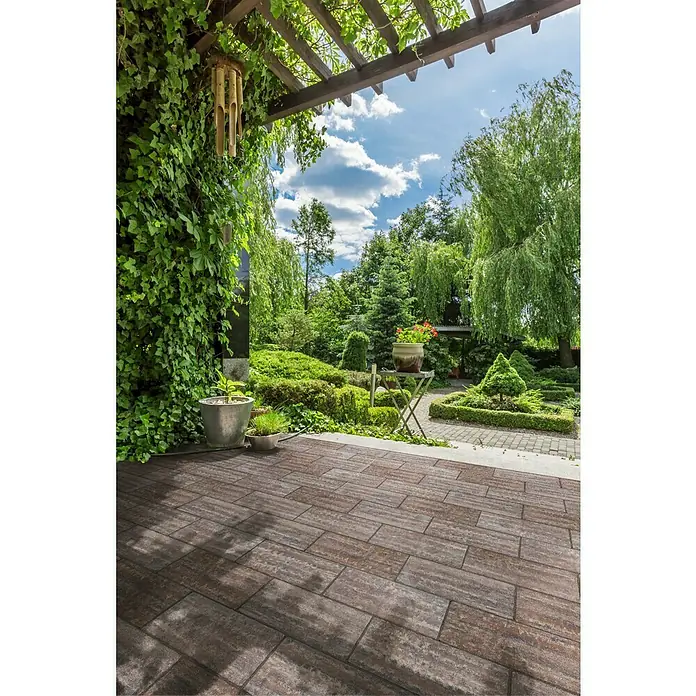 Terrassenplatte Latina - 48 x 24 x 3 cm, Mediterran, Beton - Eine Terrasse mit braunem Pflaster und üppigem Grün bietet eine idyllische Außenansicht. Ein perfekter Ort zum Entspannen und Genießen der Natur.