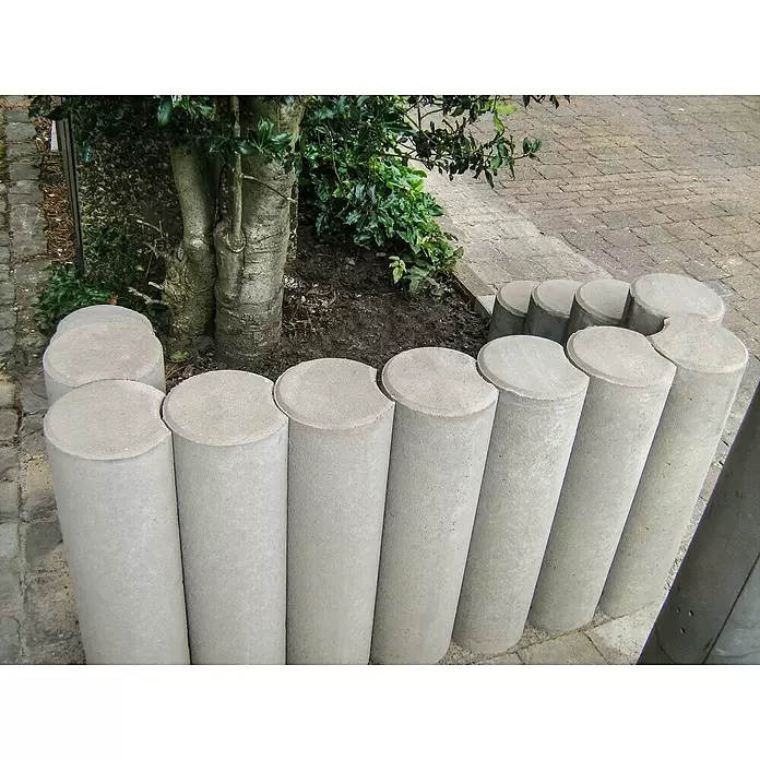 Diephaus Rundpalisade - Ø x H: 20 x 100 cm, Grau, Beton - Graue zylindrische Beton-Gartenrandeinfassungen, die einen Baum- und Pflanzenbereich an einem gepflasterten Weg umrunden.