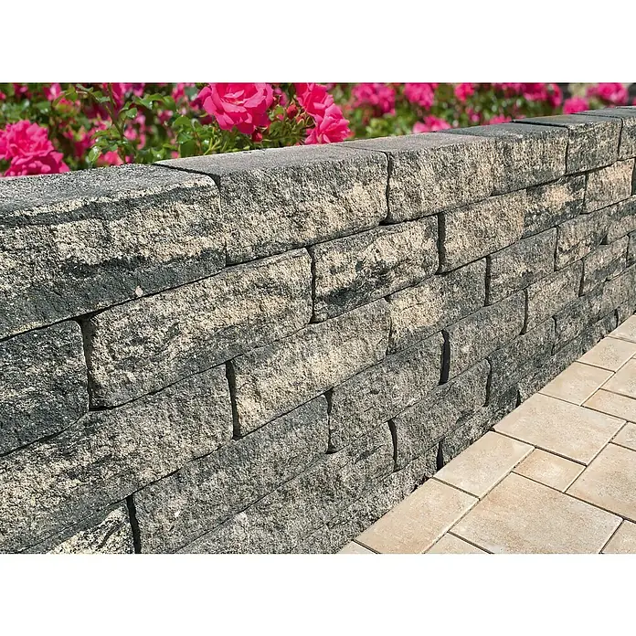 Diephaus Stamford Mauerstein - 35 x 20 x 15 cm, Schwarz/Weiß, Beton - Nahaufnahme einer stabilen, gestuften Steinmauer mit rosafarbenen Rosen im Hintergrund, ideal für Garten- und Landschaftsgestaltung.