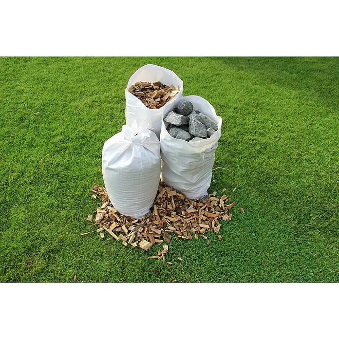 Gewebesack - 60 x 105 cm, Polypropylen, 5 Stk. - Drei weiße Säcke, einer gefüllt mit Steinen, einer mit Holzspänen und einer leer, stehen auf einer Rasenfläche.