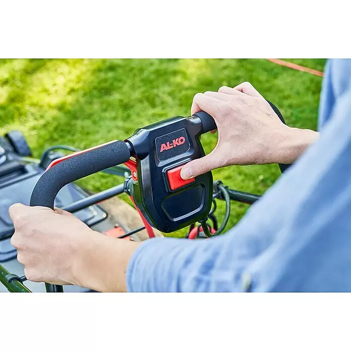 AL-KO Comfort Elektro-Rasenmäher - 1.600 W, Schnittbreite: 38 cm - Nahaufnahme von Händen, die einen schwarzen und roten AL-KO Rasenmähergriff mit rotem Startknopf bedienen.