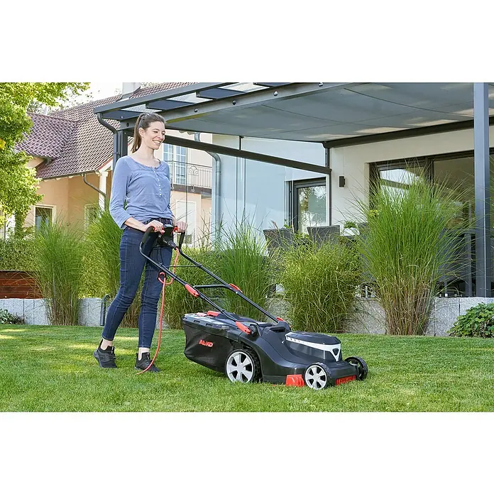 AL-KO Comfort Elektro-Rasenmäher - 1.600 W, Schnittbreite: 38 cm - Frau mäht Rasen mit AL-KO Rasenmäher im Garten eines modernen Hauses.
