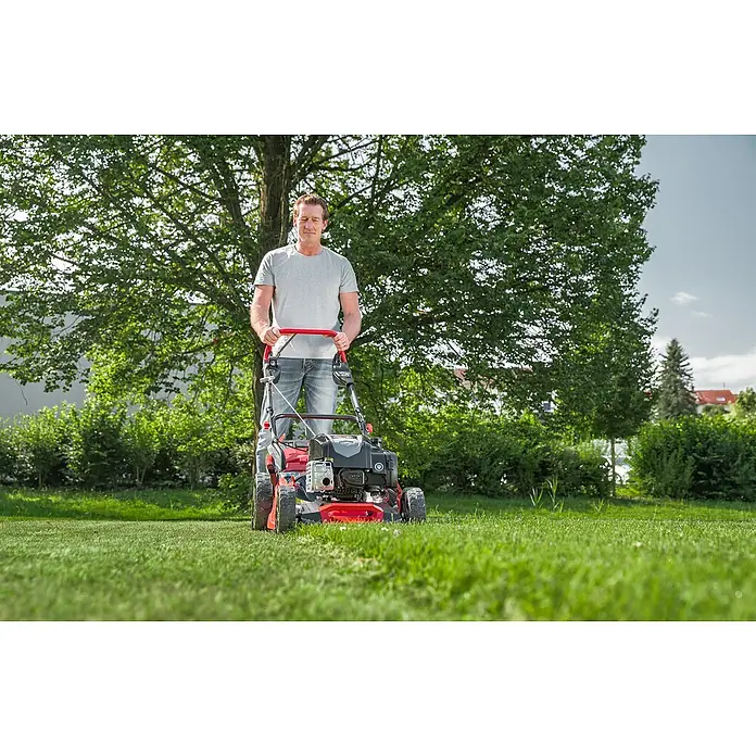 AL-KO Premium Benzin-Rasenmäher 521 SP-A - 2,6 kW, 166 cm³, Schnittbreite: 51 cm - Mann mäht den Rasen mit einem roten Rasenmäher vor einem grünen Garten.