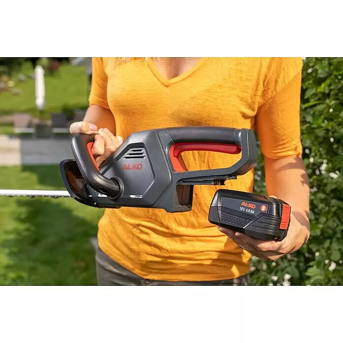 AL-KO Bosch Home & Garden Compatible Akku-Heckenschere HT 1845 - 18 V, Li-Ionen, 1 Akku, Schnittlänge: 45 cm - Person hält eine grau-rote AL-KO Heckenschere und einen schwarzen 18V 4.0Ah AL-KO Akku.