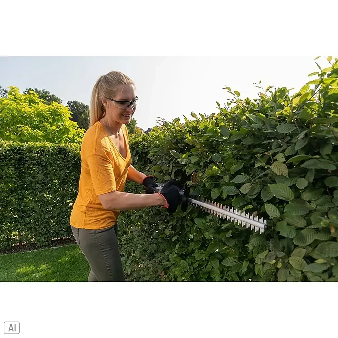 AL-KO Bosch Home & Garden Compatible Akku-Heckenschere HT 1845 - 18 V, Li-Ionen, 1 Akku, Schnittlänge: 45 cm - Eine Frau schneidet eine Hecke mit einer Heckenschere, wobei sie Schutzbrille und Handschuhe trägt, um sich zu schützen.