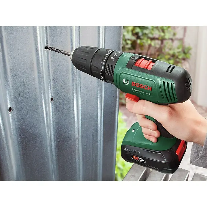 Bosch Power for All 18V Maschinenpaket - Akku-Schlagbohrschrauber EasyImpact 18V-40 + gratis Starter-Kit - Eine Bosch EasyImpact 18V-40 Akku-Bohrmaschine bohrt ein Loch in eine Metallplatte. Das Gerät ist grün und schwarz mit roten Akzenten.