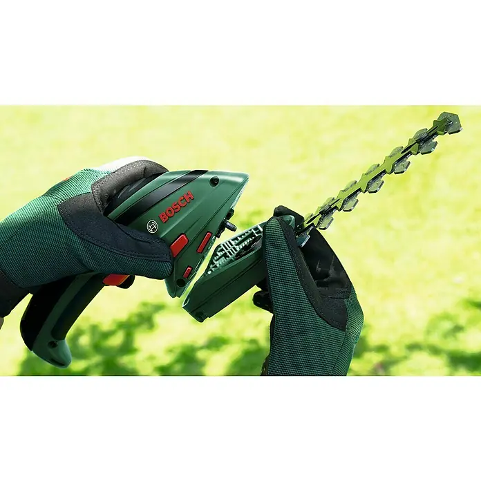 Bosch Podadora de batería - 3,6 V, Iones de litio, 1,5 Ah, 1 batería, Anchura de la hoja: 8 cm, Duración de la batería: 50 min - Primer plano de unas tijeras inalámbricas para césped y arbustos Bosch sujetadas por dos manos enguantadas, con foco en la cuchilla.