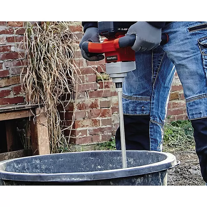 Einhell Mörtelrührer - Länge: 60 cm, Durchmesser Rührer: 120 mm - Person mischt Material in schwarzem Behälter im Freien mit rotem und grauem Einhell Akku-Rührwerk.