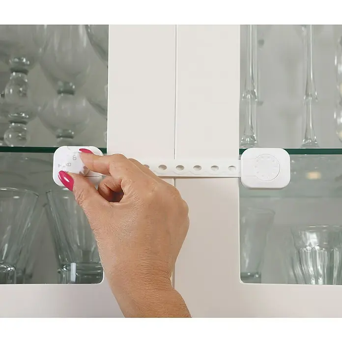 Dreambaby Multifunktionsverschluss Twist n Lock - Kleben, 2 Stk. - Eine Hand betätigt ein weißes Schranksicherheitsschloss an einer Glasschranktür, um Kinder zu schützen.