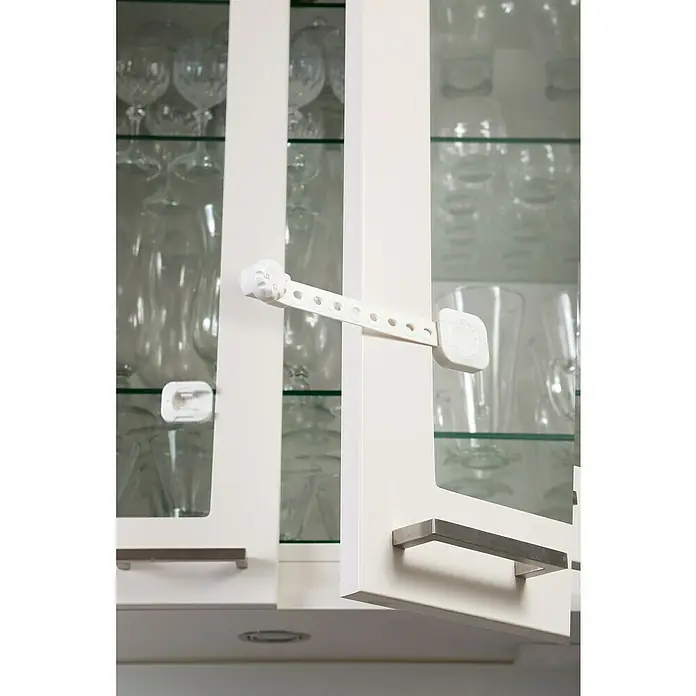 Dreambaby Multifunktionsverschluss Twist n Lock - Kleben, 2 Stk. - Diese Aufnahme zeigt einen weißen Schranksicherungsgurt an einem weißen Schrank, der die Sicherheit des Inhalts gewährleisten soll.