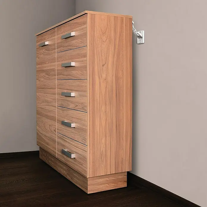 Dreambaby Kippsicherung Scharniere - Weiß - Foto eines Holzschranks mit mehreren Schubladen und silbernen Griffen, der an einer Wand mit einer Steckdose steht.