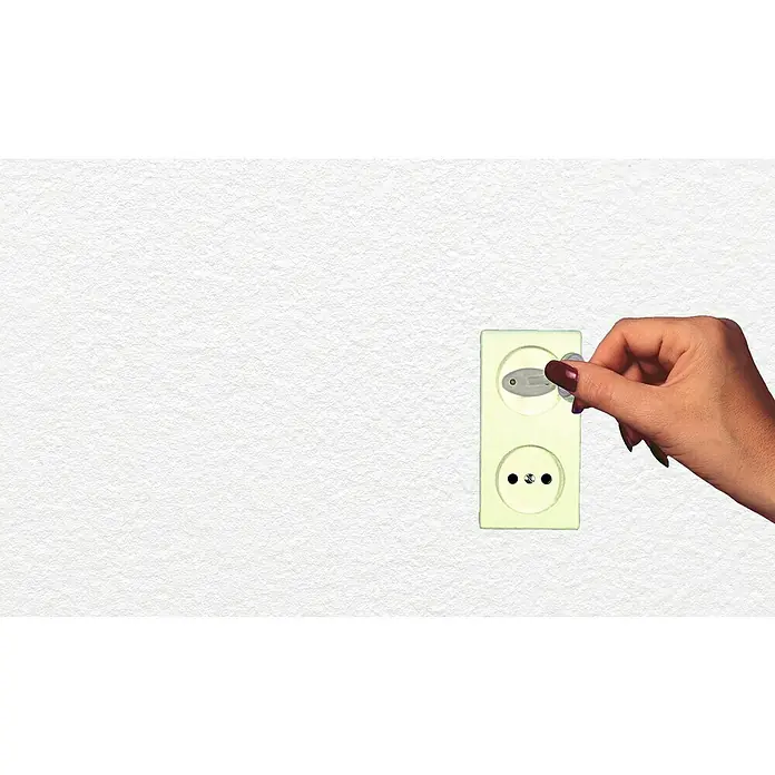 Dreambaby Kindersicherheits-Set 35 -tlg. - Weiß - Eine Hand, die einen Kinderschutzstecker in eine gelbliche Steckdose steckt, um Kindern Sicherheit zu gewährleisten.