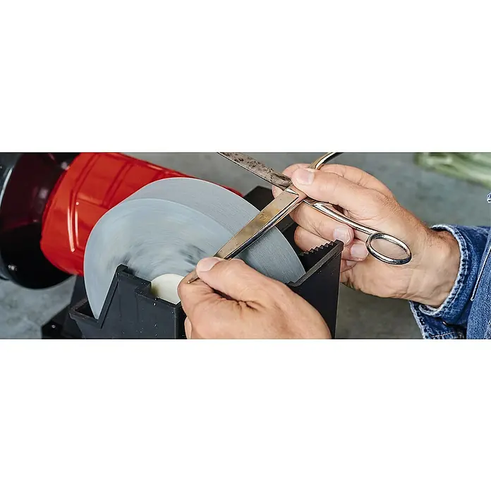 Einhell Schleifscheibe - Durchmesser: 175 mm, Körnung: 200, Durchmesser Bohrung: 20 mm - Bild einer Schleifmaschine beim Schärfen einer Schere, Fokus auf Präzision.