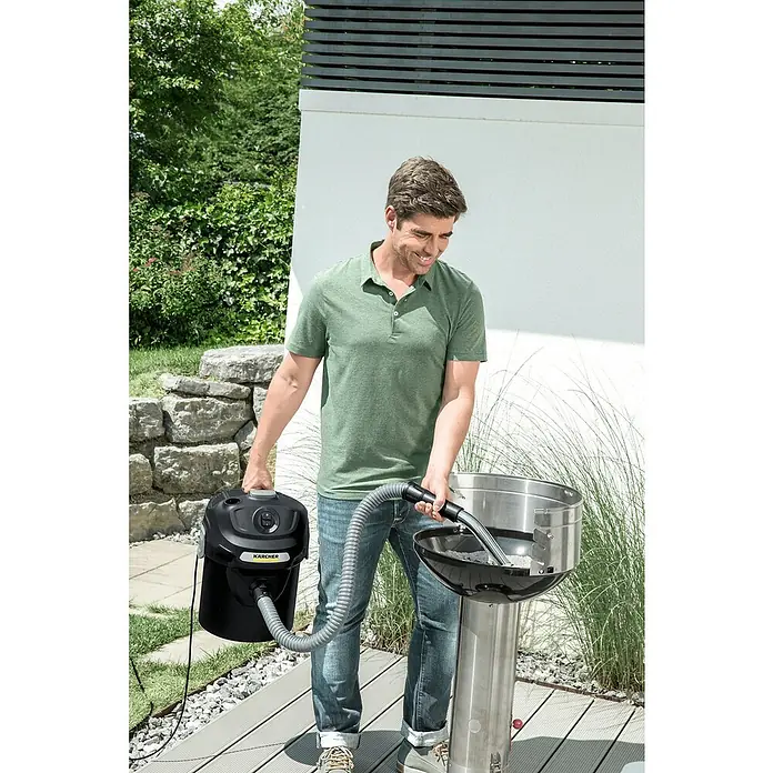 Kärcher Elektro-Aschesauger AD 2 - Leistungsaufnahme: 600 W - Ein Mann, der einen Kärcher Aschesauger zum Reinigen eines Grills im Freien benutzt. Der Sauger ist schwarz mit gelbem Kärcher-Logo.