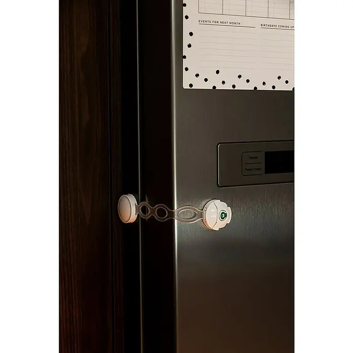 Dreambaby Multifunktionsverschluss EZY-Check - Farbe: Weiß - Das Bild zeigt einen Kühlschrank mit einer Kindersicherung, die an der Tür befestigt ist, um zu verhindern, dass Kinder den Kühlschrank öffnen.