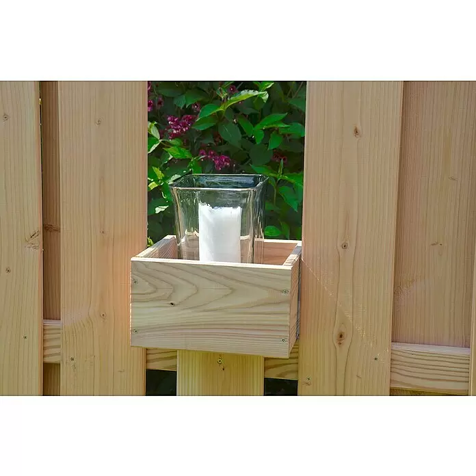 T & J Pflanzkasten Aalborg - 21 x 24 x 14 cm, Holz, Lärcheoptik - Heller Holzkasten an einem Zaun, der ein Glaswindlicht mit weißer Kerze enthält, mit einem Blattbusch im Hintergrund.