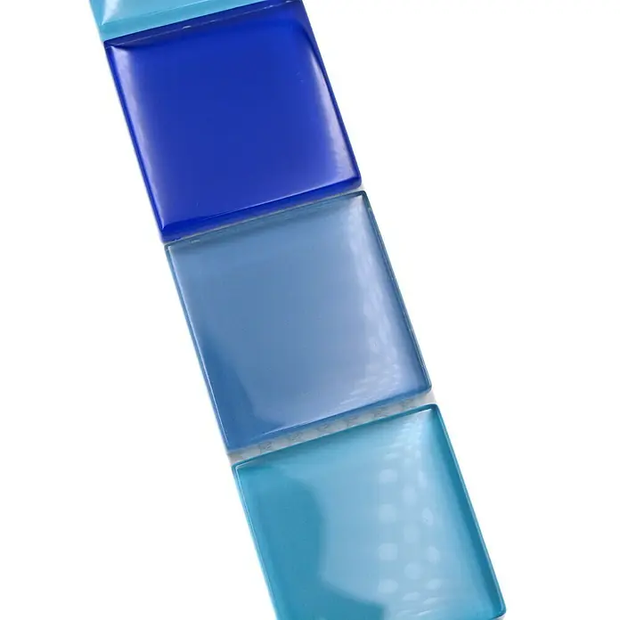 Fliesenbordüre Vision BO NB19480 - 4,8 x 30 cm, Blau, Glänzend - Nahaufnahme von drei blauen Glasmosaikfliesen, die in verschiedenen Blautönen von dunkel nach hell abgestuft sind.