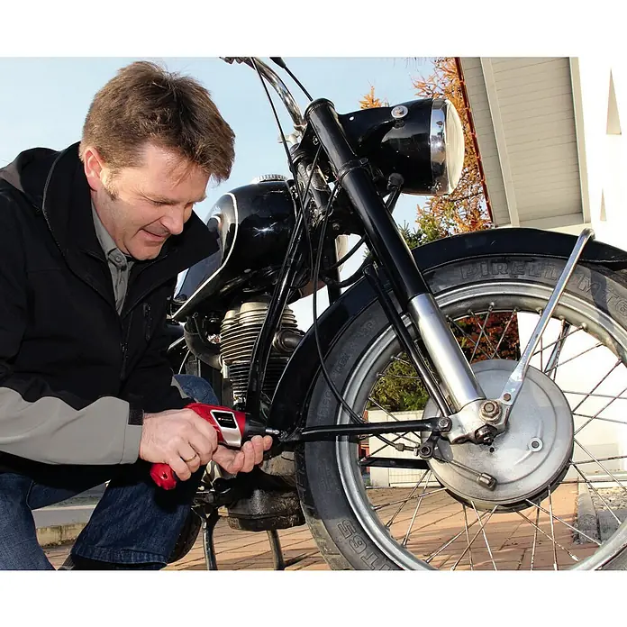 Einhell Akkuschrauber TC-SD 3,6 Li - 3,6 V, 1 Akku, 1,5 Ah - Ein Mann repariert ein Motorrad mit einem roten Akkuschrauber. Der Schrauber ist das zentrale Element.