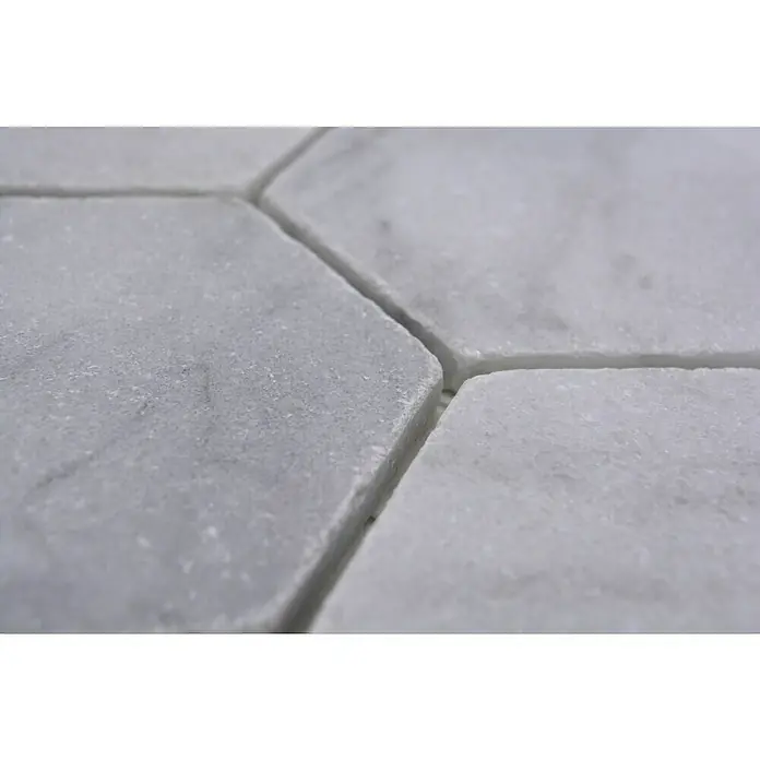 Mosaikfliese Hexagon Ibiza White Antique Marble XNT HX14219,9 x 26,2 cm, Weiß, Matt - Nahaufnahme von hellgrauen Marmorfliesen mit sichtbaren Maserungen und Fugen. Die Fliesen sind sechseckig und liegen dicht aneinander.