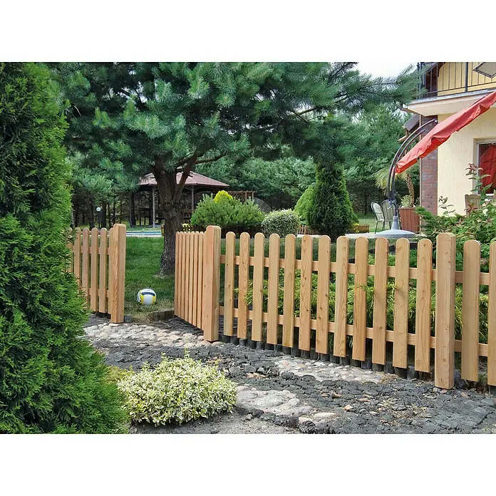 T & J Vorgartenzaun Anholt - 4,2 x 180 x 80 cm, Holz, Natur - Holzzaun im Garten. Der Zaun ist hellbraun und besteht aus vertikalen Latten. Im Hintergrund sind Bäume und ein Pavillon zu sehen.