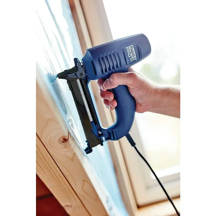 Rapid Kombi-Elektrotacker R553 PRO - Klammertiefe: 8 mm - 20 mm, Elektrisch, Schachtel - Ein blauer Rapid Pro R653 Elektrotacker befestigt eine transparente Folie an einem Holzrahmen. Das Werkzeug liegt gut in der Hand.