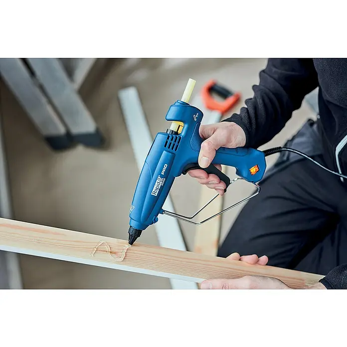 Rapid Heißklebepistole EG 320 PRO - Durchmesser Klebepatrone: 12 mm, 195 °C, 180 W - Eine blaue Rapid Pro EG320 Heißklebepistole wird verwendet, um Klebstoff auf ein Holzstück aufzutragen.