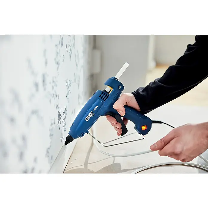 Rapid Heißklebepistole EG 320 PRO - Durchmesser Klebepatrone: 12 mm, 195 °C, 180 W - Das Bild zeigt eine Rapid PRO EG320 Heißklebepistole, die von einer Hand bedient wird, um Leim auf eine Oberfläche aufzutragen.