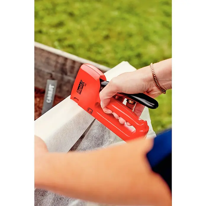 Rapid Handtacker R53E - Klammertiefe: 4 mm - 10 mm, Geeignet für: Klammern Typ 53 - Nahaufnahme eines Rapid R53 Tacker, der verwendet wird, um Stoff an einem erhöhten Gartenbeet zu befestigen. Das Werkzeug ist rot mit einem schwarzen Griff.
