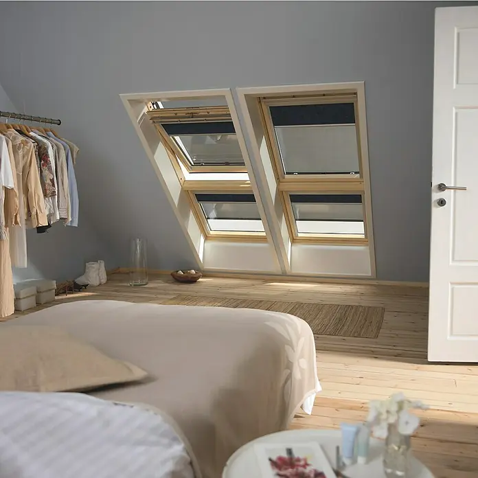 Velux Dachfenster-Markise Schnurzug MAG PK34 5060 - Farbe: Uni Schwarz - 5060, Manuell - Ein Schlafzimmer mit zwei Dachfenstern, die Licht hereinlassen. Die Fenster haben Verdunkelungsrollos, die für Privatsphäre sorgen.