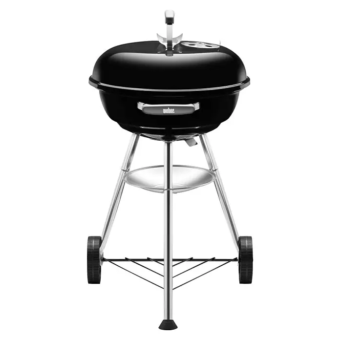 Weber Barbacoa redonda con tapa Compact Kettle - Diámetro de la superficie de la parrilla: 47 cm, Negro - Barbacoa Weber negra sobre un soporte metálico plateado con ruedas y estante para facilitar la movilidad.