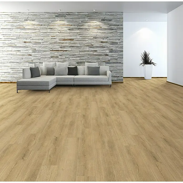 Rodapié Roble Dakota - 2,2 m x 13 mm x 90 mm - Imagen de una sala de estar con suelo laminado marrón claro, un sofá gris y una pared de piedra decorativa.