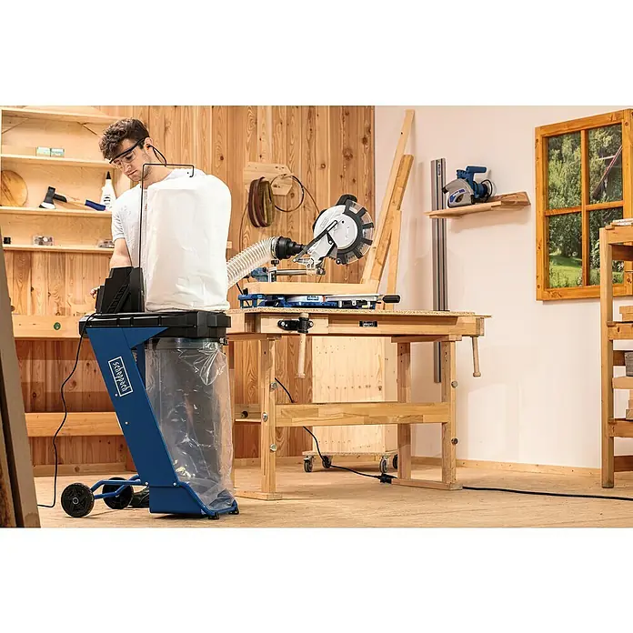 Scheppach Equipo de aspiración DC500 - 550 W, Volumen bolsa de polvo: 75 l - Imagen de taller con un sistema de aspiración Scheppach y una sierra ingletadora sobre un banco de trabajo, permitiendo un trabajo de la madera eficiente.