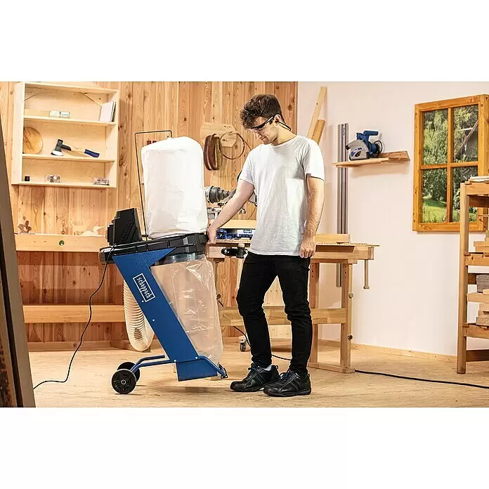 Scheppach Absauganlage DC500 - 550 W, Staubbeutelvolumen: 75 l - Blauer Scheppach Staubsammler mit weißem Filterbeutel und transparentem Auffangsack, bedient von einem Mann in einer Holzwerkstatt.
