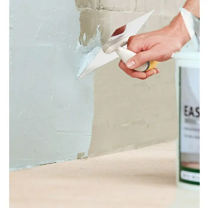 Ultrament Reaktivabdichtung Easy Dicht - 10 kg, 1-komponentig - Ein Handwerker glättet eine Wand mit einer Spachtelmasse und einem Glättspachtel für eine gleichmäßige Oberfläche.