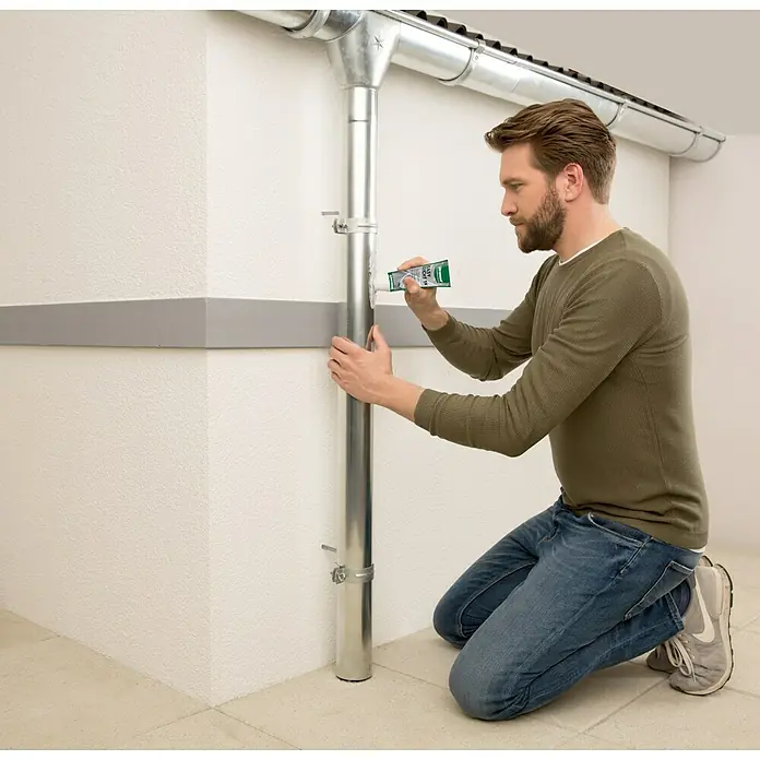 Ultrament Reaktivabdichtung Easy Dicht - 180 g, 1-komponentig - Mann dichtet ein Fallrohr mit Dichtmittel ab. Das Rohr ist silbern und wird an der Wand befestigt.