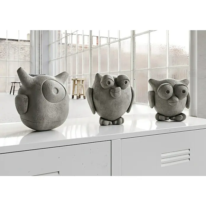 Ultrament Beton-Knetmasse Knet Beton - Hellgrau, 2,5 kg - Drei graue Eulenstatuen aus Beton stehen auf einem weißen Schrank vor einem Fenster. Die Eulen haben unterschiedliche Designs und Größen.