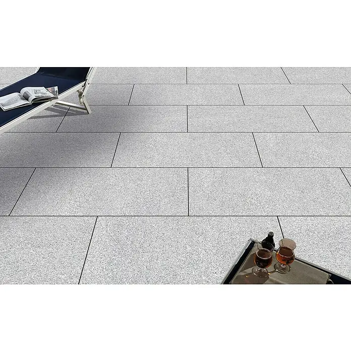 Terrassenfliese Cera 2.0 - 60 x 120 x 2 cm, Fortezza Montorfano, Matt - Eine Nahaufnahme von grauen Pflastersteinen, die ein elegantes und modernes Ambiente für den Außenbereich schaffen. Sonnenliege und Getränke inklusive.
