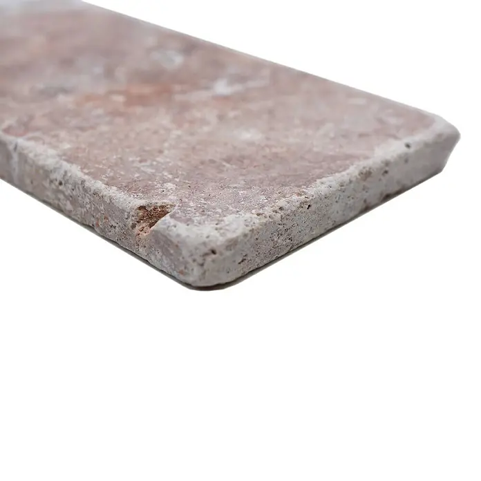 Antikmarmorfliese Travertin Rosso - 7,5 x 15 cm, Rot, Matt - Nahaufnahme einer rechteckigen, rosafarbenen Natursteinfliese mit unregelmäßiger Oberfläche und abgerundeten Kanten.