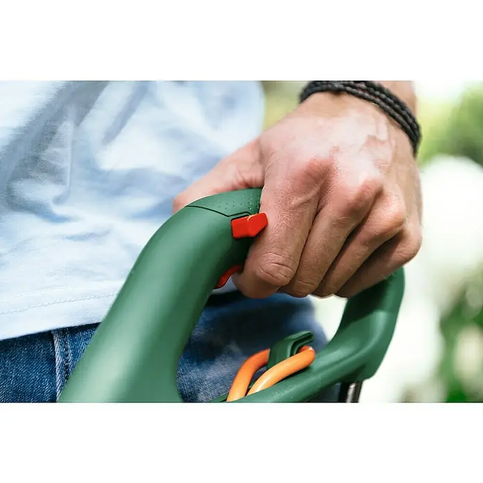 Bosch Recortabordes eléctrico EasyGrassCut 23 II - 280 W, Ancho de corte hilo: 23 cm - Primer plano de una mano sujetando el mango de un cortasetos verde con botones rojos, ideal para jardinería.