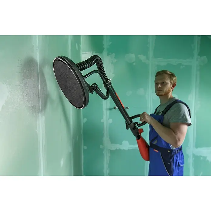Einhell Schleifgitter-Set5 Stk. - Ein Mann verwendet einen Langhalsschleifer, um eine Wand zu bearbeiten. Das Werkzeug ist speziell für Gipskartonplatten konzipiert.