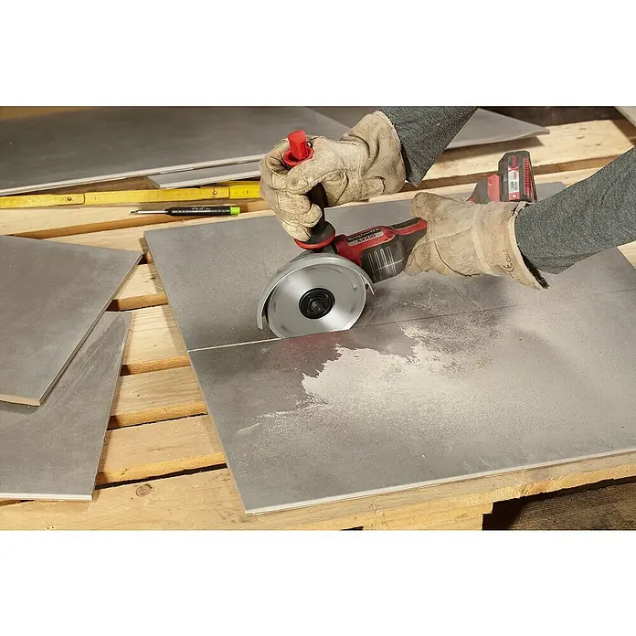 Einhell Diamant-Trennscheibe - Durchmesser Scheibe: 150 mm, Stärke Scheibe: 1,6 mm - Fliesenleger schneidet eine Fliese mit einer AXXIO-Fliesensäge, um präzise Anpassungen vorzunehmen. Schutzkleidung ist dabei unerlässlich.
