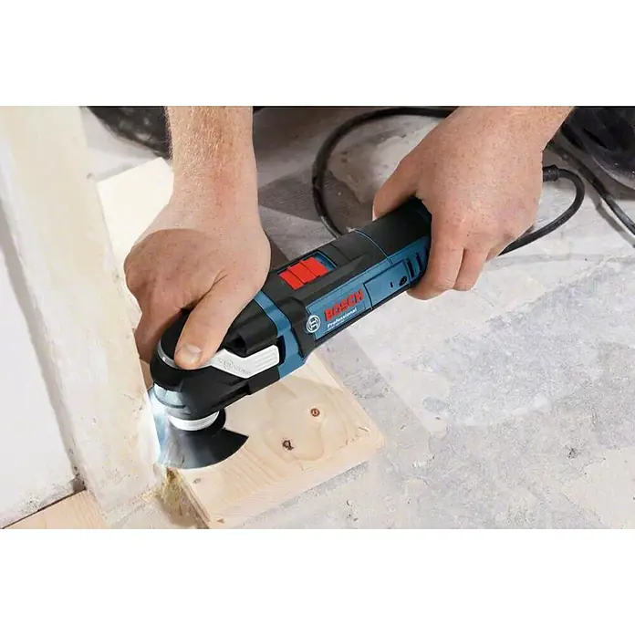 Bosch Professional Multiherramienta GOP 40-30 + accesorios - 400 W, Sistema STARLOCK - Primer plano de una multiherramienta Bosch cortando madera, sostenida por dos manos.