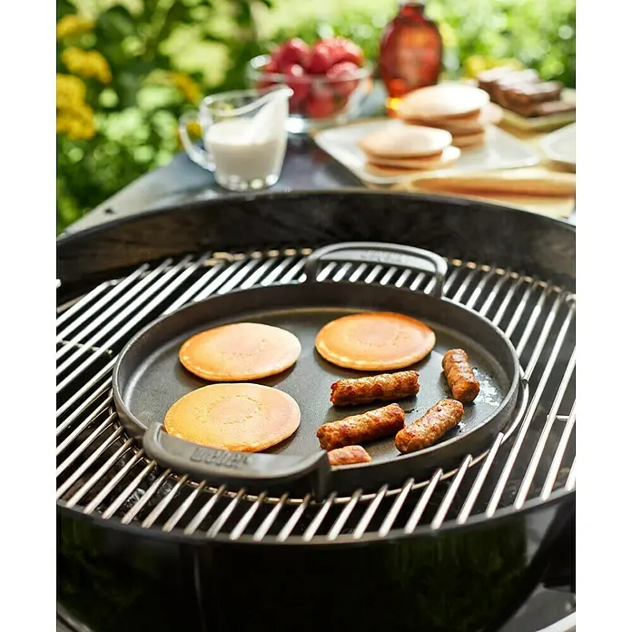 Weber Gourmet BBQ System Grillpfanne - Durchmesser: 38,6 cm, Gusseisen - Pfannkuchen und Würstchen werden auf einer Weber Grillplatte auf einem Grill zubereitet.