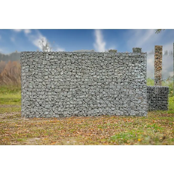 Gabiona Gabione - 200 x 20 x 100 cm, Metall, Maschenbreite: 50 mm, Maschenhöhe: 50 mm - Das Bild zeigt eine Gabionenwand, gefüllt mit grauen Steinen, im Freien. Gabionen sind vielseitig einsetzbar im Garten- und Landschaftsbau.