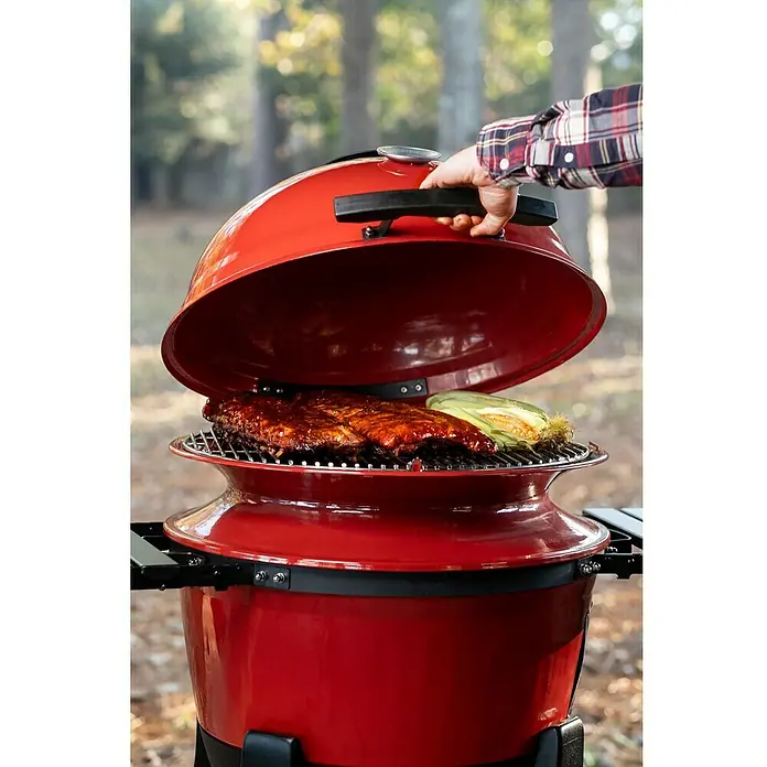 Kamado Joe Holzkohlegrill Kettle Joe - Durchmesser Grillfläche: 55 cm, Rot - Ein roter Kugelgrill mit geöffnetem Deckel, auf dem Rippchen und Maiskolben auf dem Rost liegen, bereit zum Genießen.